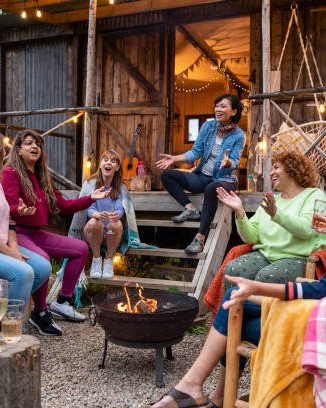 Women gathered around a firepit in warm conversation